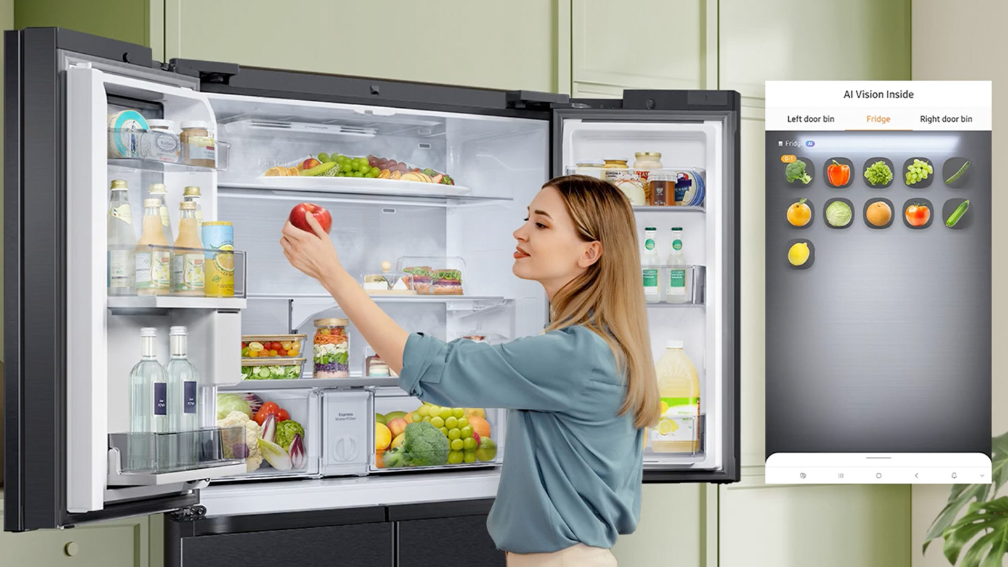 Frau greift Apfel aus gefülltem Kühlschrank mit geöffneten French Door Flügeltüren