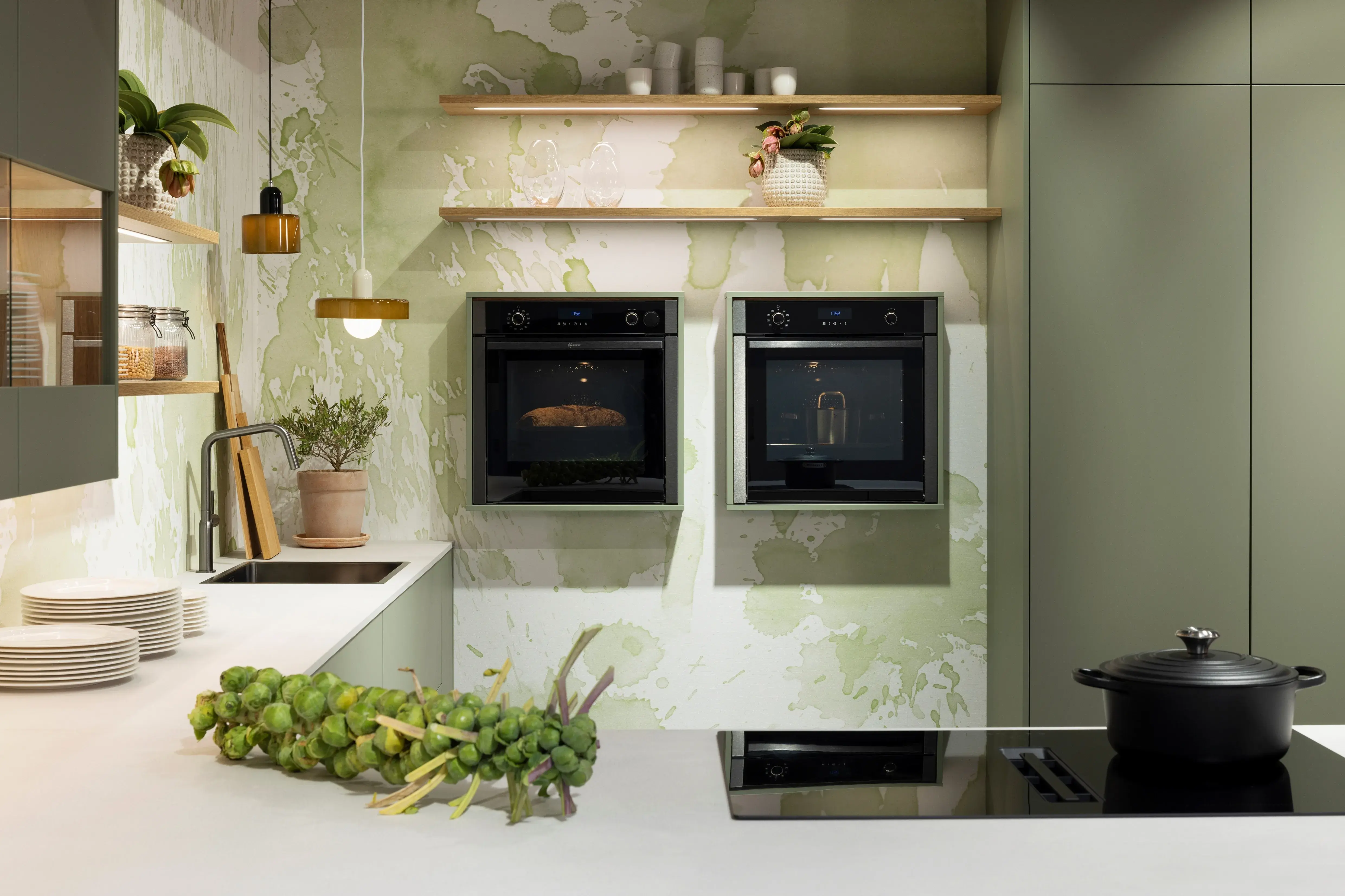 APL: 794 Beton Seidengrau NB (Xtra Ceramic) Korpus: 198 Eiche Sierra Front: Senso 495 Lack, Olive Premium matt Geräte: Neff Slide&Hide Armatur: Gessi  Spüle: Teka  Features: Trendfarbe Olive, Push to open, Tapete, neuer Schubkasten, Wandeinbau Backofen, beleuchtete Regale, beleuchtete Vitrinen, Weinflaschenregal, Schubkästen und Korpus in Eiche Sierra, Premium matte Oberfläche mit Antifingerprint, Nischenrückwand in Rillenoptik.